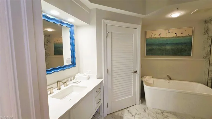 Bathroom with vanity, a freestanding bath, and light marble finish floors