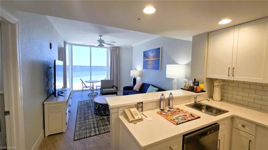 Kitchen featuring open floor plan, white cabinets, dishwasher, light countertops, and a peninsula