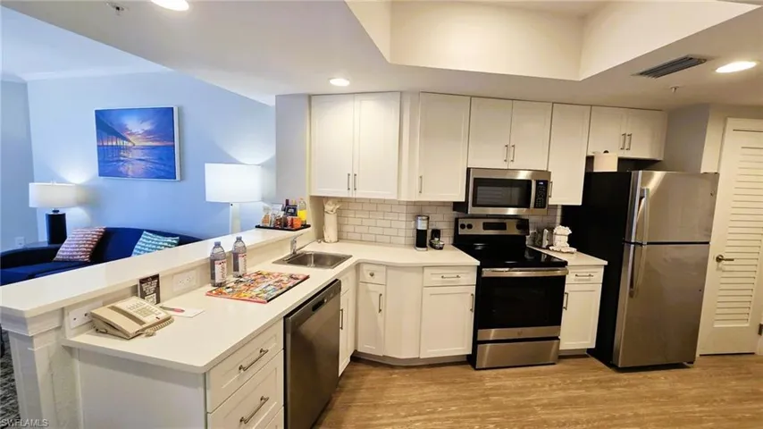 Kitchen featuring stainless steel appliances, white cabinetry, light wood finished floors, tasteful backsplash, and recessed lighting