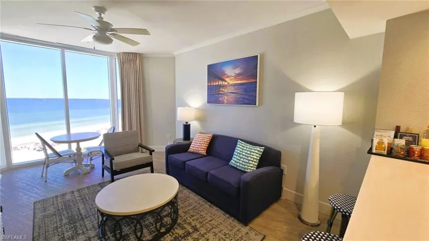 Living room with a Gulf beach view, ornamental molding, wood finished floors, floor to ceiling windows, and ceiling fan