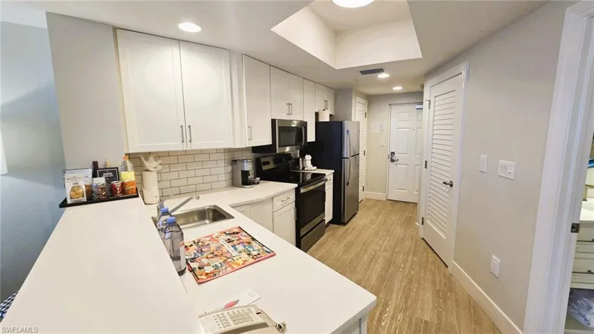 Kitchen with light countertops, white cabinets, stainless steel appliances, and recessed lighting