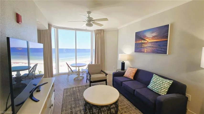 Living area featuring expansive sliding glass doors, wood finished floors, a ceiling fan, and a textured wall