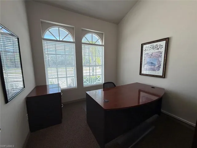 Office area with dark carpet and vaulted ceiling