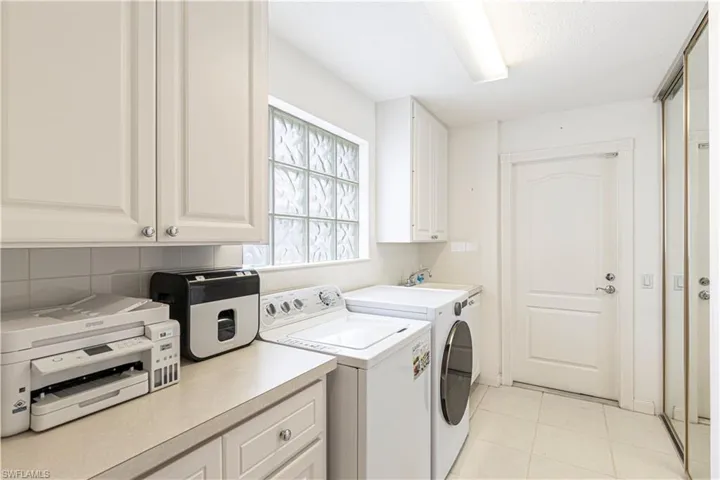 Clothes washing area with cabinets, independent washer and dryer, and light tile patterned floors