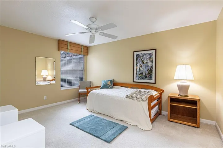 Bedroom featuring ceiling fan, light carpet, and a textured ceiling
