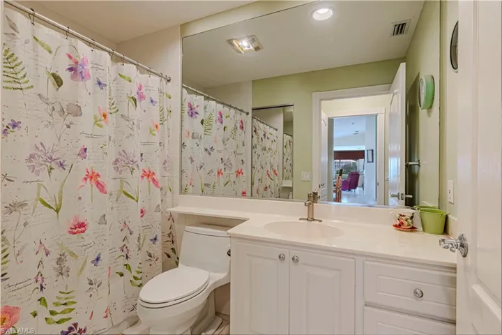 Bathroom featuring a shower with curtain, vanity, and toilet