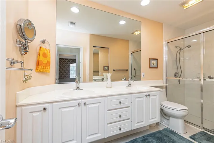 Bathroom featuring tile patterned flooring, vanity, toilet, and a shower with door
