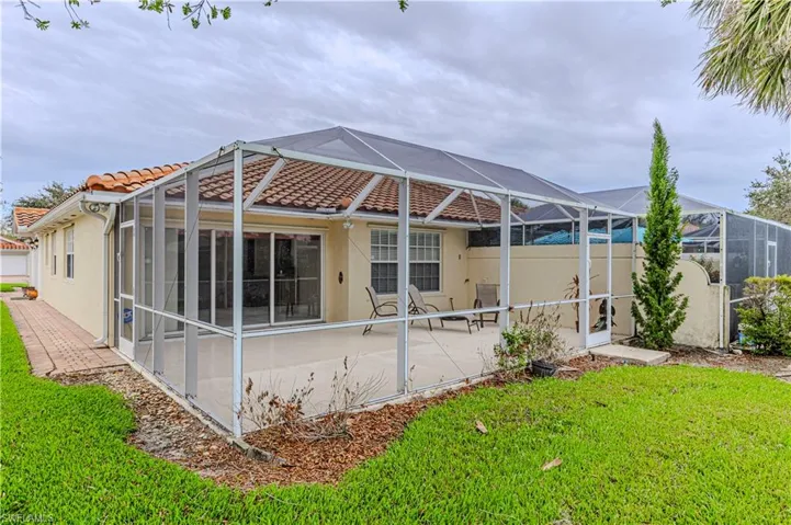 Back of house featuring a yard, a patio, and glass enclosure