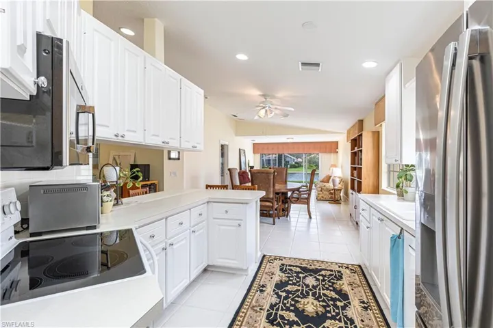 Kitchen with kitchen peninsula, white cabinetry, vaulted ceiling, and appliances with stainless steel finishes