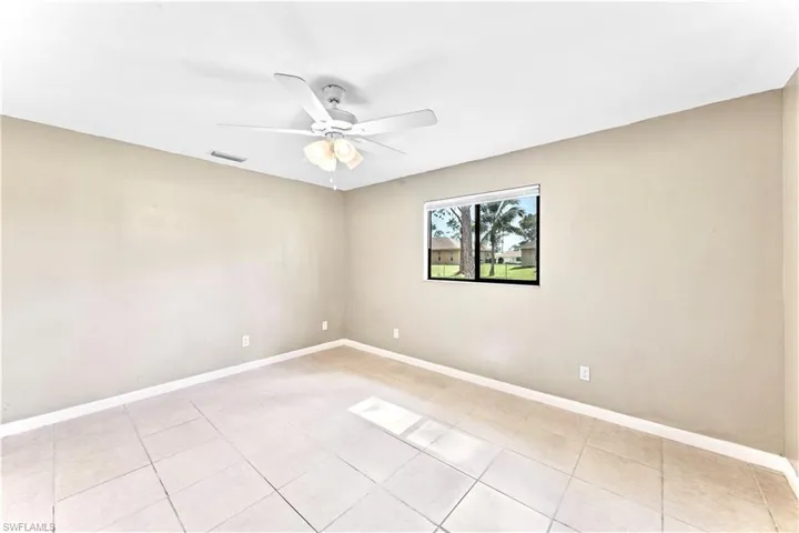 Empty room with ceiling fan and light tile patterned floors