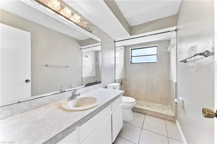 Bathroom featuring vanity, toilet, tile patterned floors, and a tile shower