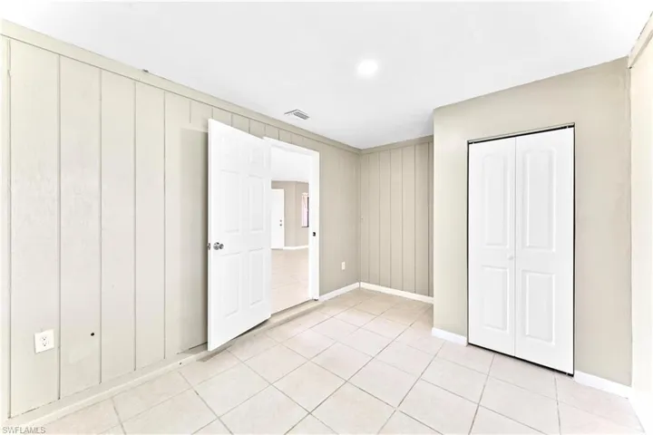 Unfurnished bedroom featuring light tile patterned floors and wooden walls