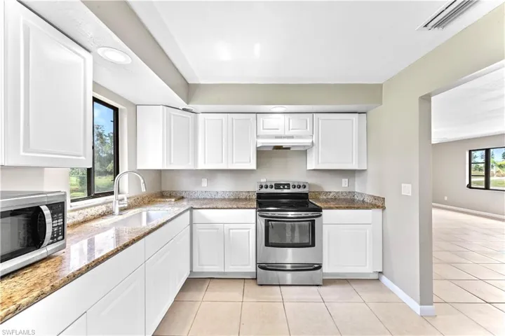 Kitchen with appliances with stainless steel finishes, white cabinetry, sink, and plenty of natural light