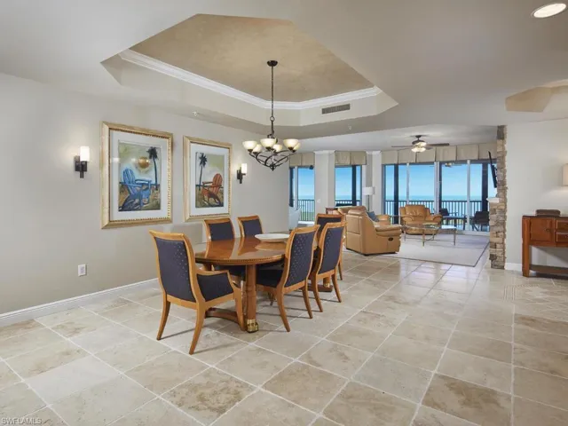 Dining room with crown molding, a chandelier, a tray ceiling, ceiling fan, and light tile patterned floors