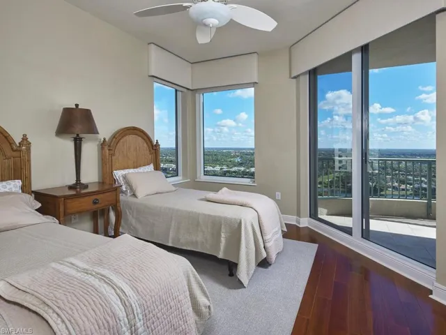 Bedroom with access to exterior, dark wood-style flooring, and a ceiling fan
