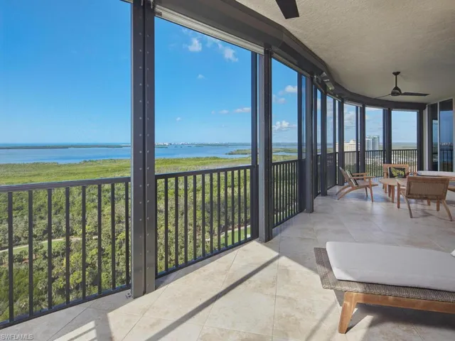 Sunroom featuring a wall of windows, a water view, a textured ceiling, and tile patterned floors
