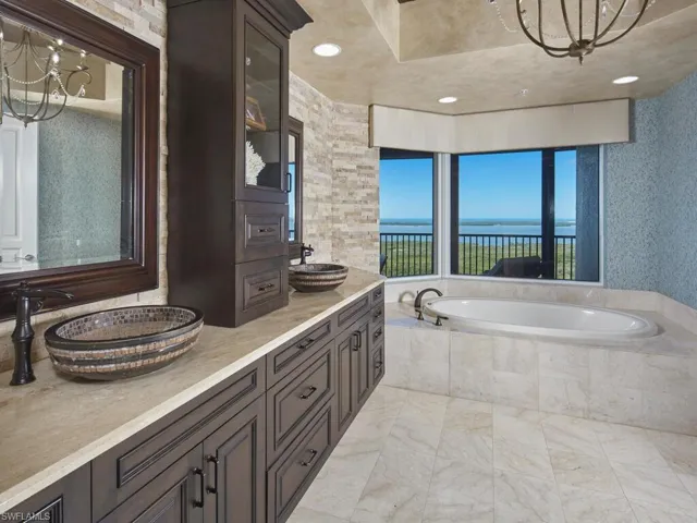 Full bathroom with a chandelier, a bath, double vanity, and a water view