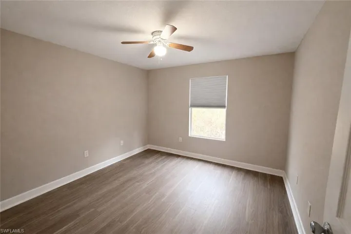 Unfurnished room with dark wood-style flooring and a ceiling fan
