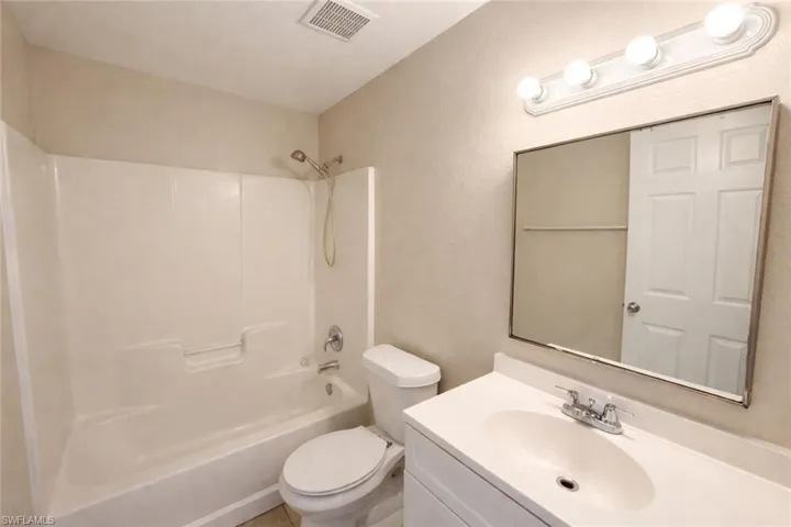 Full bath with vanity, shower / bathtub combination, and a textured wall