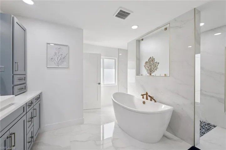Full bathroom featuring light marble finish flooring, vanity, a marble finish shower, recessed lighting, and a soaking tub