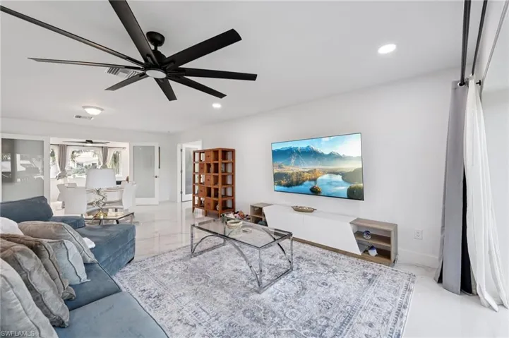 Living room with recessed lighting, ceiling fan, and light marble finish flooring