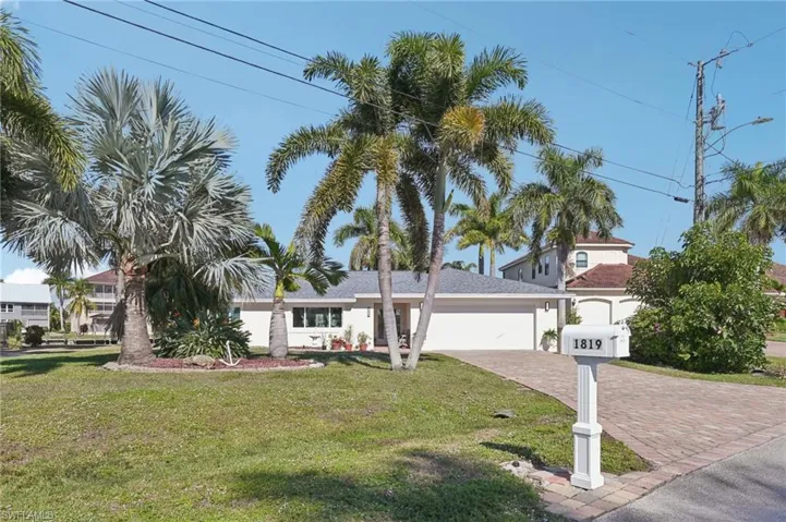 View of front of home featuring a garage, a front yard, decorative driveway, and stucco siding