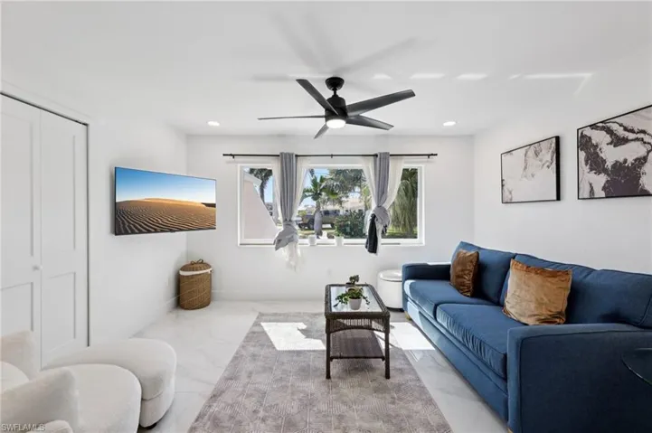 Living room with marble look tiles, ceiling fan, and recessed lighting