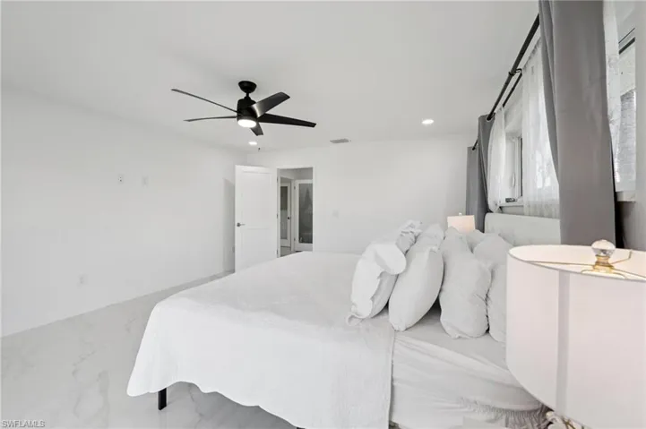 Bedroom with recessed lighting, ceiling fan, and marble look tile flooring