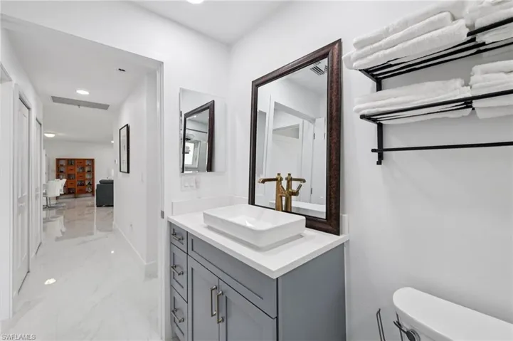 Half bath featuring vanity, light marble finish floors, and recessed lighting