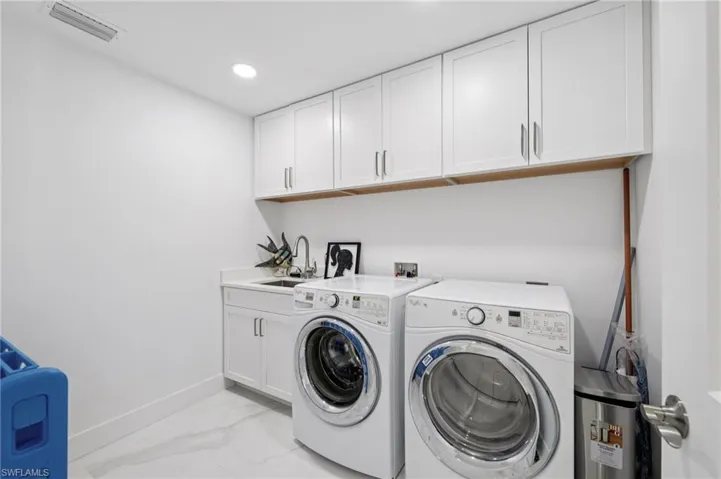 Washroom featuring light marble finish floors, separate washer and dryer, cabinet space, and recessed lighting