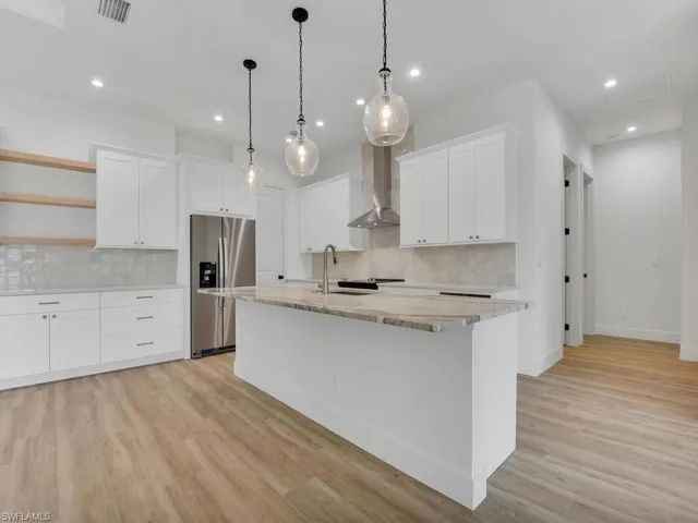 Kitchen featuring decorative backsplash, open shelves, white cabinetry, stainless steel refrigerator with ice dispenser, and recessed lighting