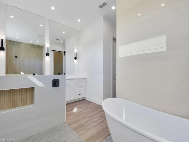 Full bath with vanity, a freestanding bath, recessed lighting, light wood-type flooring, and a shower