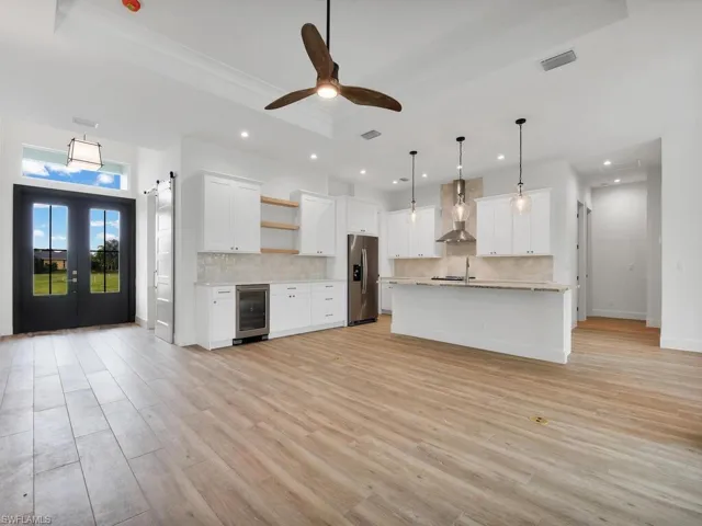 Kitchen with white cabinets, open shelves, hanging light fixtures, decorative backsplash, and light wood finished floors