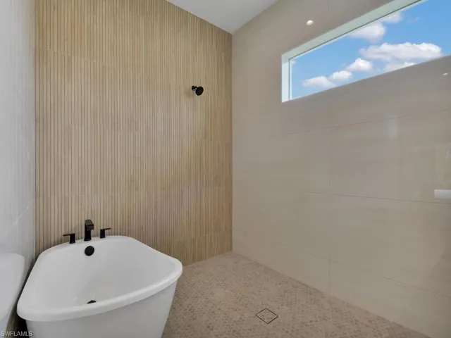 Full bathroom with a freestanding bath and tile walls