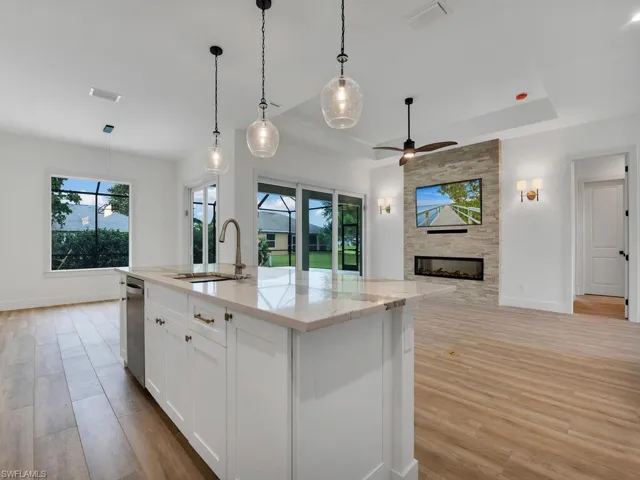 Kitchen with white cabinetry, pendant lighting, light stone counters, and open floor plan