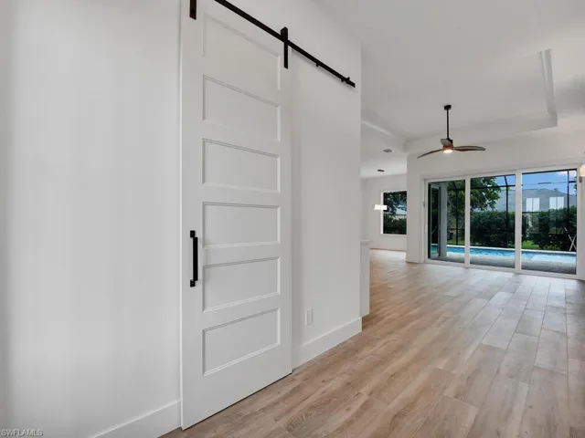 Spare room with a barn door, light wood finished floors, and a ceiling fan