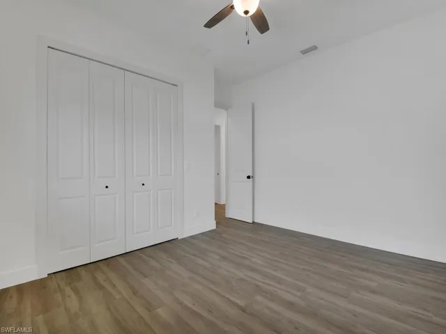 Unfurnished bedroom featuring wood finished floors, a closet, and a ceiling fan