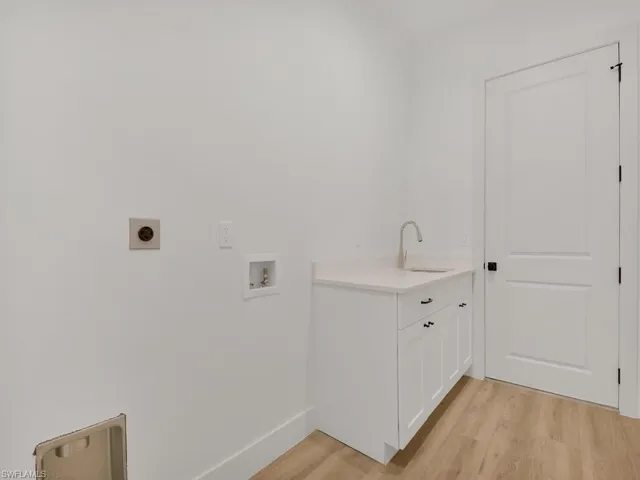 Washroom featuring light wood-style flooring, hookup for an electric dryer, hookup for a washing machine, and cabinet space