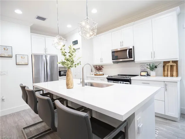Kitchen with appliances with stainless steel finishes, a breakfast bar area, a kitchen island with sink, and sink