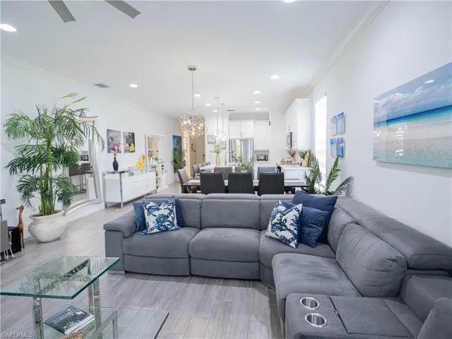 Living room featuring ceiling fan with notable chandelier, light hardwood / wood-style floors, and crown molding