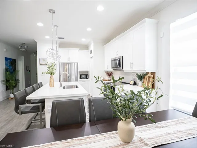 Kitchen featuring sink, white cabinets, a kitchen breakfast bar, appliances with stainless steel finishes, and decorative light fixtures