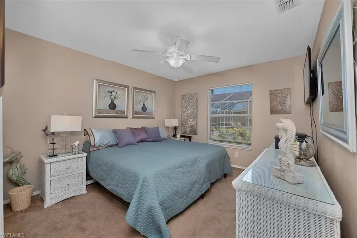 Carpeted bedroom featuring visible vents, baseboards, and ceiling fan