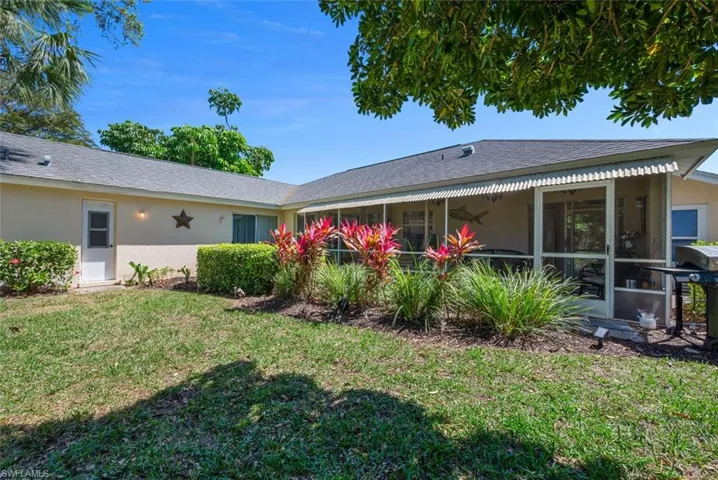 Rear view of property with stucco siding, a yard, and a sunroom