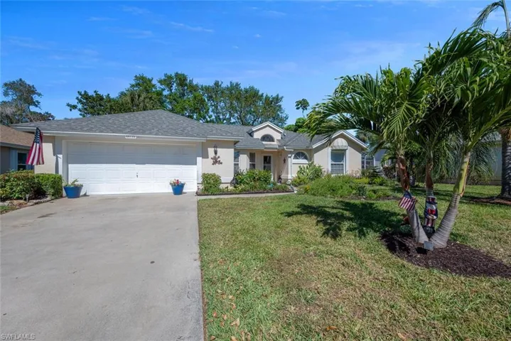 Ranch-style house with stucco siding, driveway, a garage, and a front lawn