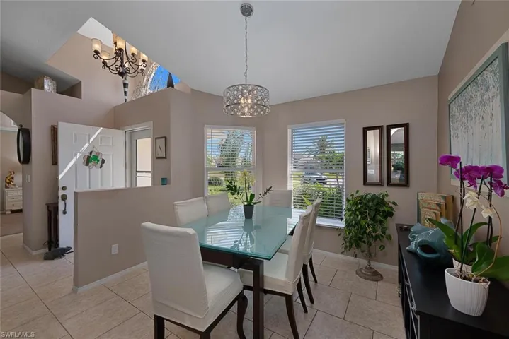 Dining area featuring light tile patterned flooring, a notable chandelier, and baseboards