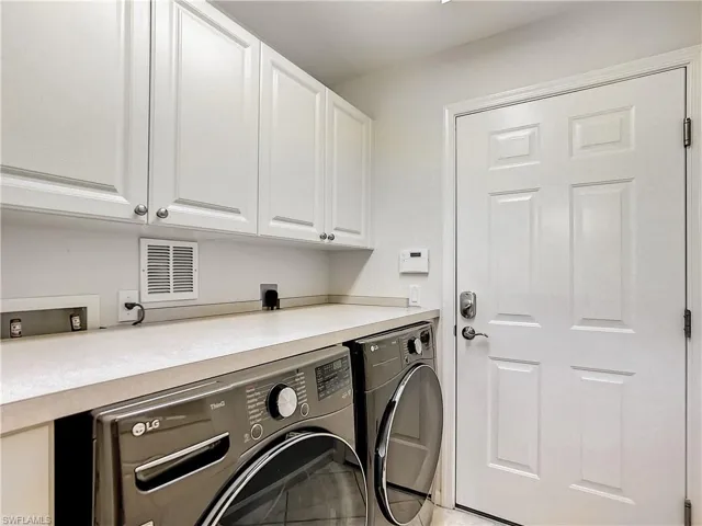 Laundry room featuring cabinets and front load washing machine and dryer.  It also has sink.