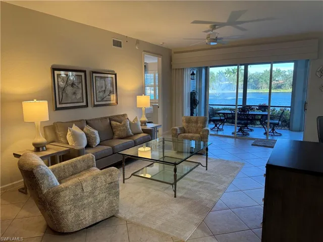 Living room with a water view, a ceiling fan, and light tile floors
