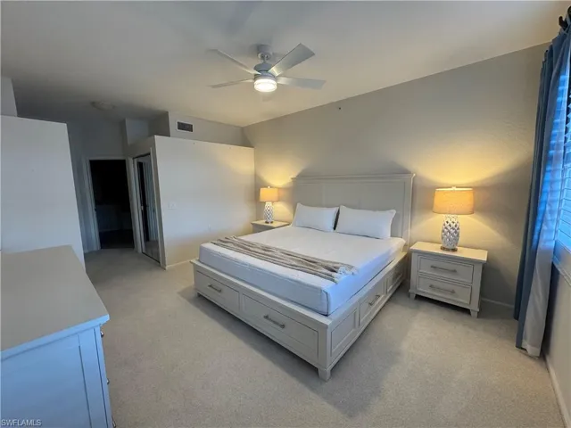 Bedroom with light colored carpet, ceiling fan with ensuite bathroom and two separate closets