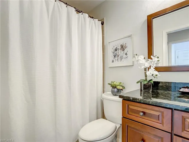 Bathroom featuring shower/tub combo and cherry vanity & granite countertops