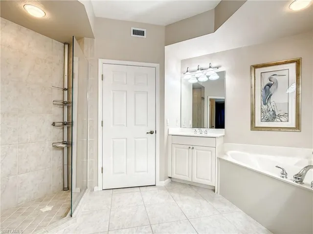 Bathroom featuring separate shower with frameless shower doors, soaking tub, separate water closet and two vanities.